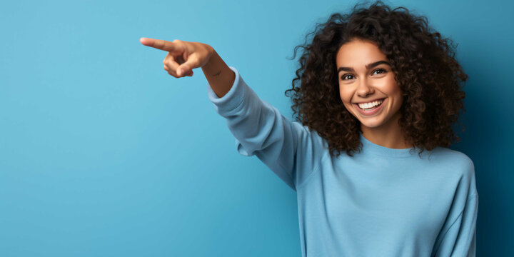 a young woman pointing on a plain blue background, fashio