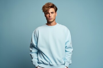 Isolated Portrait of a Fictional Male Model Wearing a Large Oversized Light Blue Colored Sweatshirt on a Plain Blank Background. Generative AI.