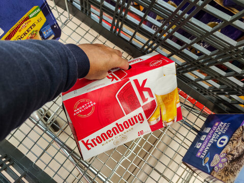 Close up on customer putting a pack of Kronenbourg beer in their shopping cart at the supermarket