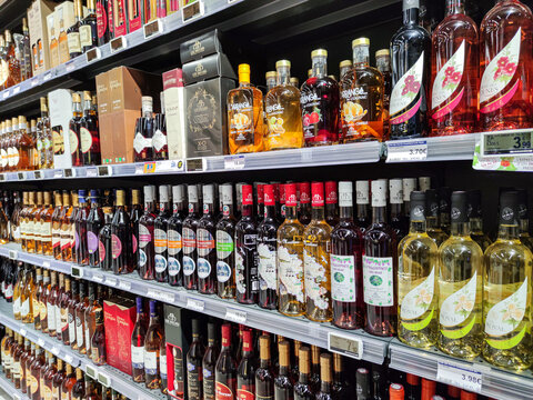 Side view of a shelf with various alcoholic beverages (Cognac, local wines..) in a French supermarket