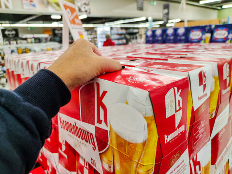 Closeup of Man hand buying a Pack of Kronenbourg beer on aile of French supermarket