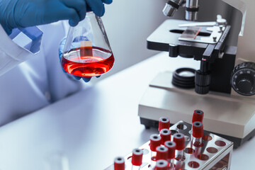 Hands of a doctor or female doctor collecting blood sample tubes from rack with analyzer in lab. Doctor holding blood test tube in research laboratory red blood cells