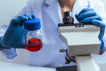 Hands of a doctor or female doctor collecting blood sample tubes from rack with analyzer in lab. Doctor holding blood test tube in research laboratory red blood cells