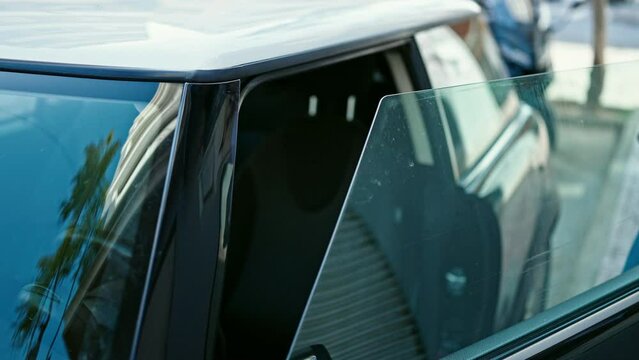Young hispanic man opening door sitting on car at street