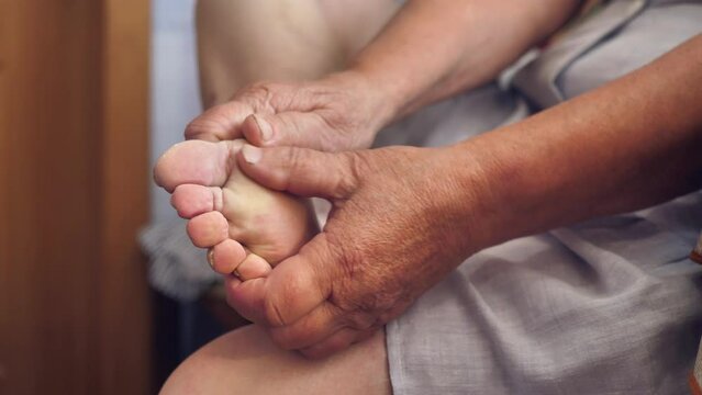 an old woman without a face, an elderly woman massages the soles of her feet.