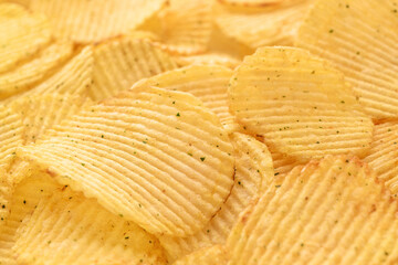 Appetizing crispy potato chips with texture background in selective focus, fast food.