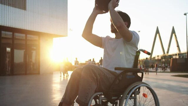 A man in a wheelchair playing with basketball with somebody off the frame