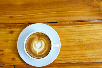 A cup of coffee latte on a brown wooden background, close up overhead view.