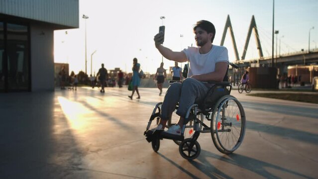 A man in a wheelchair having a videocall and showing his friend the surroundings
