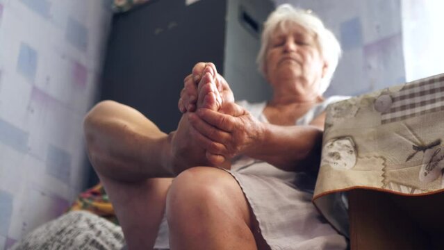 the old woman massages the soles of her feet.