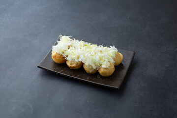 takoyaki with green onions on top of a dark gray background