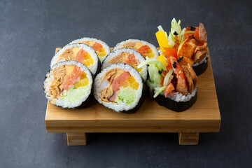 Gimbap with shrimp and various vegetables in a dark gray background