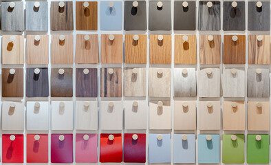 Set of colorful wooden laminate sheets hanging on material swatch wall display in material library. Color board collection for interior architecture and furniture finishing design