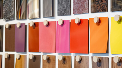 Set of colorful wooden laminate sheets hanging on material swatch wall display in material library....