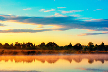 Obraz premium Picturesque sunrise over the calm water of the pond on a warm summer morning. High quality photo