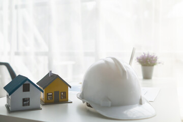 Construction engineers place plans and model homes  on desks in their offices for real estate agents to view the plans they want construction engineers to build on budget and meet client needs.