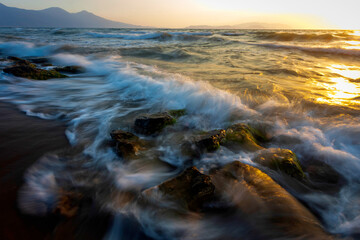 A seascape photographed with a long exposure technique at sunset.