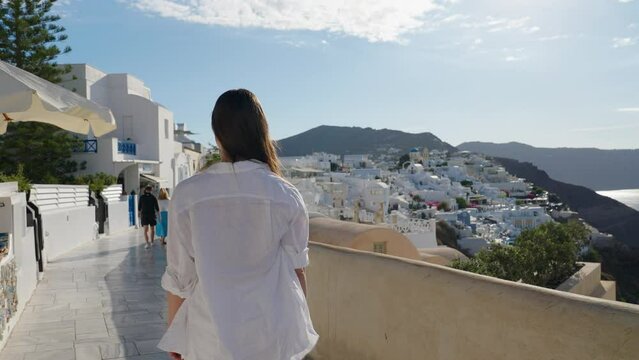 Tourist travel woman in Oia, Santorini, Greece. Happy tourist walking on stairs by famous landmark destination in Greece Santorini
