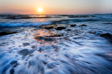 A seascape photographed with a long exposure technique at sunset.