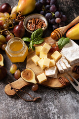 Cheese plate, still life of seasonal wine snacks. Brie cheese, fresh figs, grapes, cheese cubes,...
