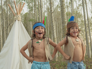 Twins enjoying playing Native American with a tepee.