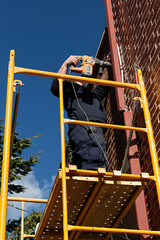 Fontanero subido a un andamio arreglando una tubería.