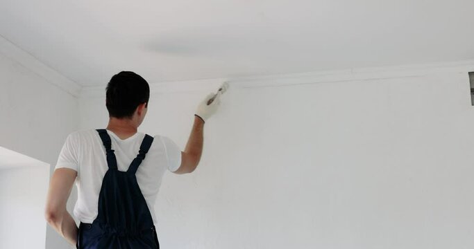 man painting wall in white color with roller