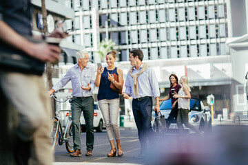 Diverse group of coworkers using a smartphone while commuting together to work in the city