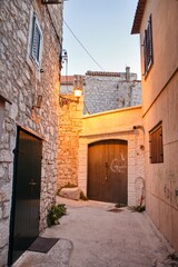 Fototapeta premium The narrow short street in idyllic fishing village of Tribunj with motorbikes, scooters and colorful houses during sunset, Croatia, Europe