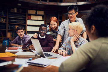 Young and diverse group of students using the laptop and studying in an university library together