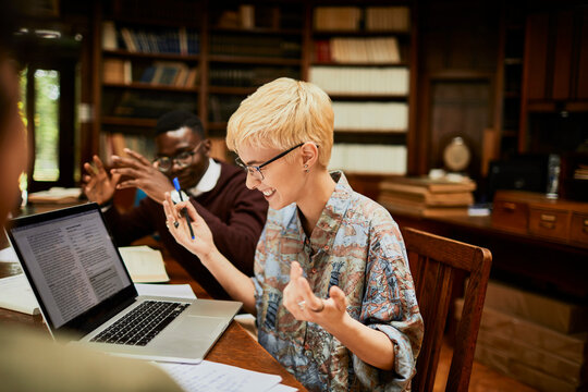 Diverse group of friends using the laptop in a college library together
