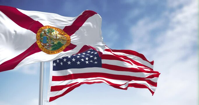 Flags of Florida and United States waving in the wind on a clear day