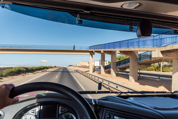 View from the driving position of a truck of a pedestrian walkway where a person crosses on a highway.