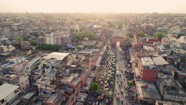 Top-angle drone moving aerial shot of a Urban suburb locality with vehicles or traffic congestion in a busy Indian city market or traditional old bazaar and people walking on the street.