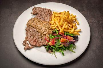 Grilled chop with bean sauce, salad and fried French fries. On a marble background.