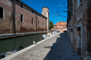 Fototapeta na wymiar Un canale lungo le mura dell'Arsenale di Venezia in una giornata di sole con delle barche ormeggiate