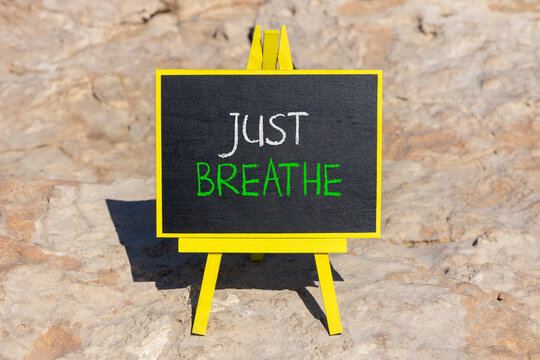 Just breathe and psychological symbol. Concept words Just breathe on beautiful black chalk blackboard on a beautiful stone background. Business psychological and Just breathe concept. Copy space