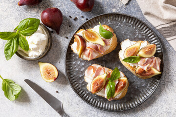 Italian appetizer recipe. Toast or bruschetta with bacon and figs, cream cheese and honey on a gray...
