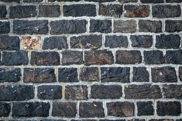 Dark stone wall background. Old black brick texture, rock floor pattern. Construction natural material, vintage granite, grunge surface, rough exterior design, abstract urban wallpaper.