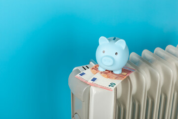 Savings concept.Money in piggy bank on radiator on blue wall background. Concept of heating season....