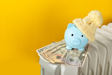 Savings concept.Money in piggy bank on radiator on yellow wall background. Concept of heating...