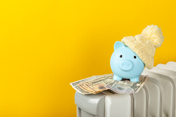 Savings concept.Money in piggy bank on radiator on yellow wall background. Concept of heating...