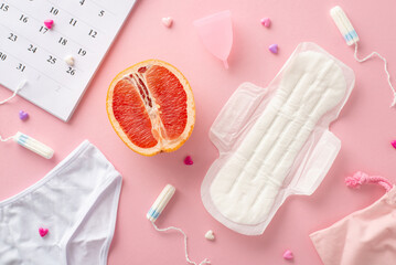 Top view pastel pink scene featuring menstrual essentials such as pad, tampons, menstrual cup, underwear, hearts, cycle calendar, grapefruit symbolizing female genitalia, ideal for advertising
