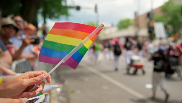 Hand hold Flag and people at pride parade. Close up shot
