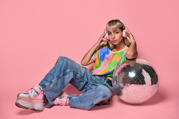 Cool woman leaning on disco ball and listening to music