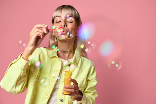 Young woman blowing soap bubbles in studio