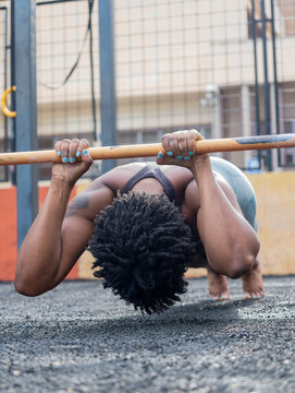 Strong unrecognizable woman doing bar plank exercise on gym ground