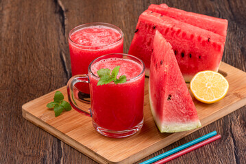 Watermelon juice with mint leaves, sliced watermelon and cocktail straws.