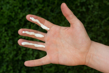 A person applying the correct amount of sunscreen for face and neck (three finger lengths).