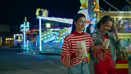 Best friends having fun together at illuminated luna park. Happy girls walking